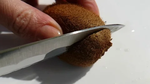 Hands slice kiwi on white Stock Footage 88319644