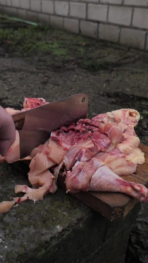 Hands slicing a chicken with a kitchen cleaver. Stock Footage 326028976
