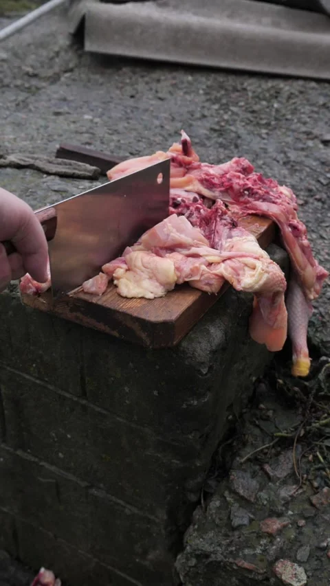 Hands slicing a chicken with a kitchen cleaver. Stock Footage 326029447