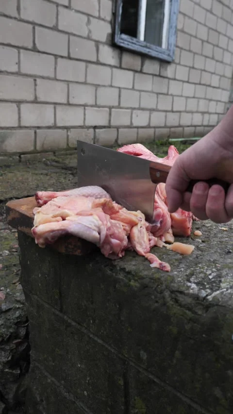 Hands slicing a chicken with a kitchen cleaver. Stock Footage 326029476