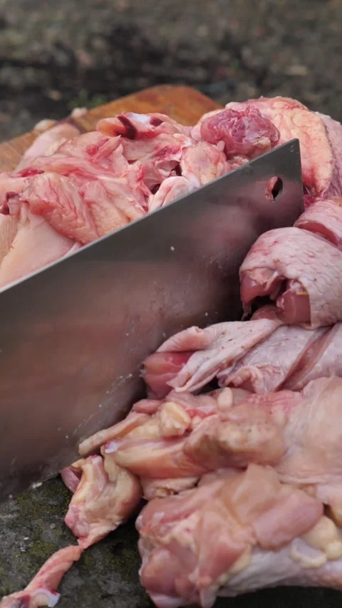 Hands slicing a chicken with a kitchen cleaver. Stock Footage 326029861