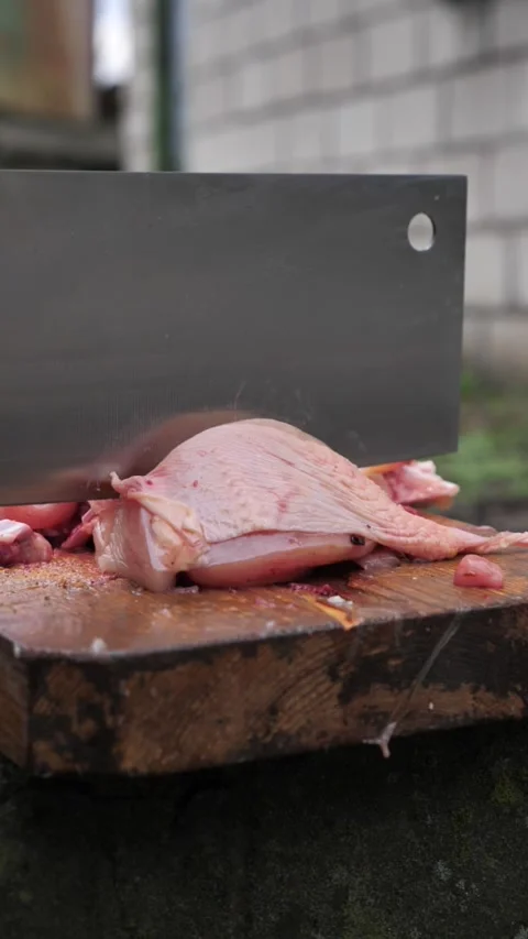 Hands slicing a chicken with a kitchen cleaver. Stock Footage 326030026