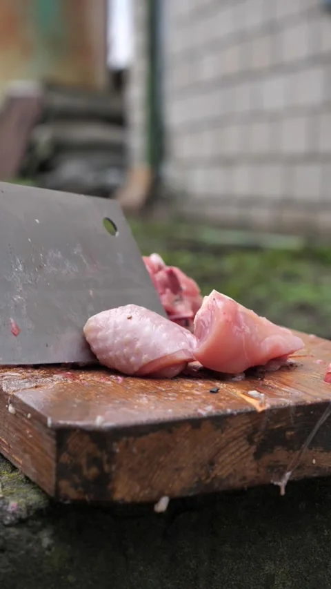 Hands slicing a chicken with a kitchen cleaver. Stock Footage 326030124