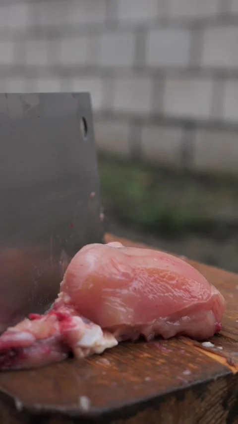 Hands slicing a chicken with a kitchen cleaver. Stock Footage 326030237