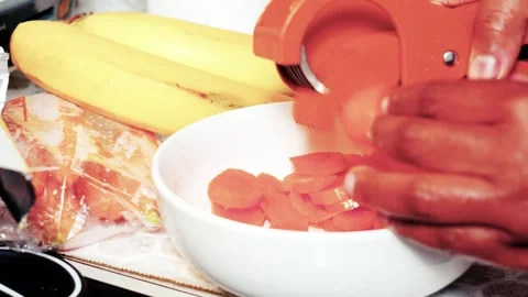 Hands slicing fresh carrots with orange multi blade kitchen gadget 库存影片 338200328