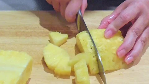Hands Slicing Fresh Pineapple Lengthwise on Wooden Board Stock Footage 345102371