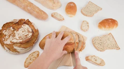 Hands Slicing Fresh Sourdough Bread on Wooden Board Overhead View Stockbeeldmateriaal 337395011