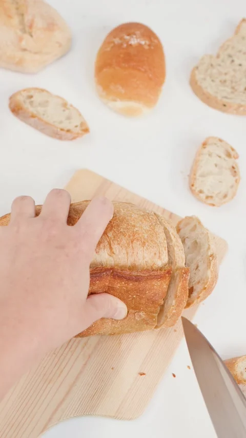 Hands Slicing Fresh Sourdough Bread on Wooden Board Stock Footage 337519435