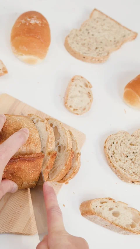 Hands Slicing Fresh Sourdough Bread on Wooden Board with Knife Stock Footage 337533023