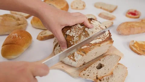 Hands Slicing Fresh Sourdough Bread on Wooden Board Stock Footage 337533075