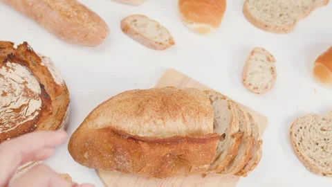 Hands Slicing Fresh Sourdough Bread on Wooden Board Stock Footage 337533222