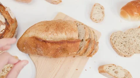 Hands Slicing Fresh Sourdough Bread on Wooden Board Over White Background Stock Footage 337690876