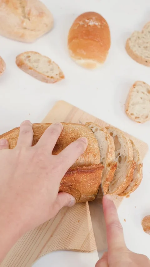 Hands Slicing Fresh Sourdough Bread on Wooden Board Overhead View Stockbeeldmateriaal 337748261