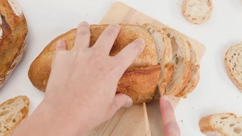 Hands Slicing Fresh Sourdough Bread on Wooden Board Over White Background Stock Footage 337748282