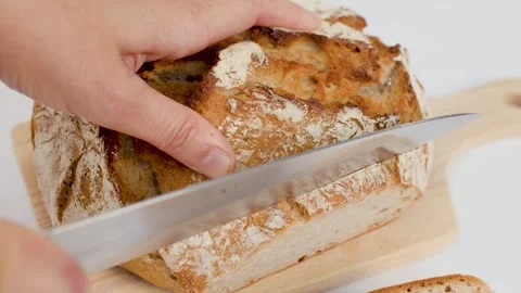 Hands Slicing Fresh Sourdough Bread on Wooden Board Stock Footage 337748438