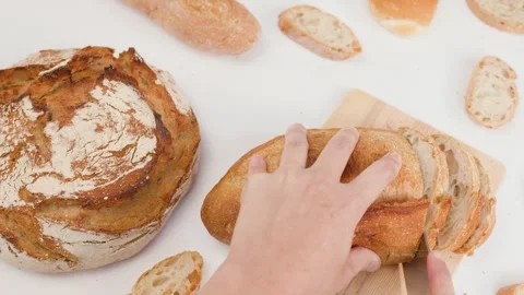 Hands Slicing Fresh Sourdough Bread on Wooden Board with Knife Stock Footage 337748504