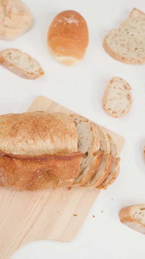 Hands Slicing Fresh Sourdough Bread on Wooden Board Over White Background Stock Footage 337770567