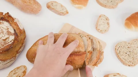 Hands Slicing Fresh Sourdough Bread on Wooden Board Over White Background Stock Footage 337860302