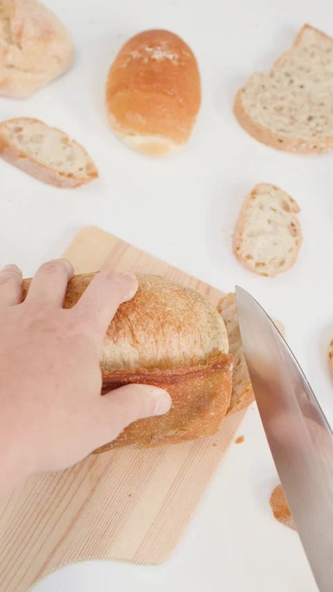 Hands Slicing Fresh Sourdough Bread on Wooden Board Stock Footage 337925847