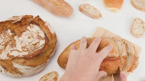 Hands Slicing Fresh Sourdough Bread on Wooden Board Overhead View Stockbeeldmateriaal 338051272