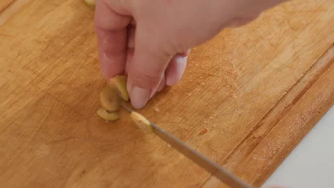 Hands slicing green olive rounds and gathering them on wooden cutting board Stock Footage 343684830