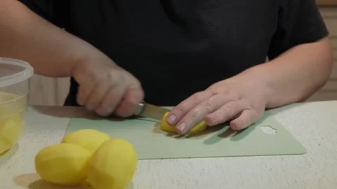 Hands slicing peeled potatoes on green cutting board Vidéo 342362736
