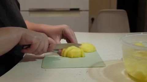 Hands slicing peeled potatoes into small cubes on cutting board Vidéo 342362761
