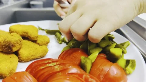 Hands slicing pickled cucumber onto plate with nuggets, close up shot Stock Footage 345166304