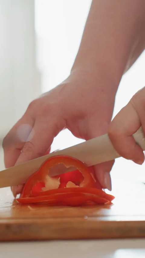 Hands slicing small red tomato on wooden cutting board with knife pressing Stock Footage 343679599