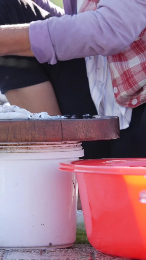 Hands slicing a small squid on a cutting board at a simple market kitchen table. Stock Footage 341408836