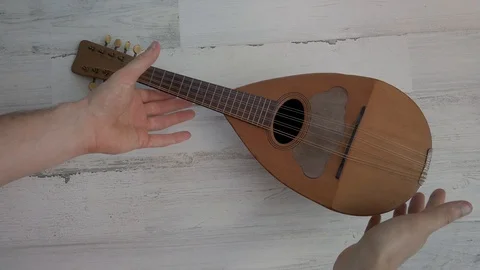 Hands slowly turn a 4 stringed wood instrument ukulele, top down, 4k. Stock Footage 115855551