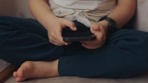 The hands of a small boy holding a phone in his hand and taping. Smart device Stock Footage 243147110