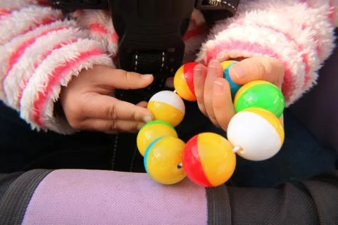 Hands of a small child holding a plastic rattle toy. Stock-Fotos
