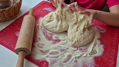 Hands of a small child kneading dough on a red silicone mat. Dough for baking Stock Footage 302253743