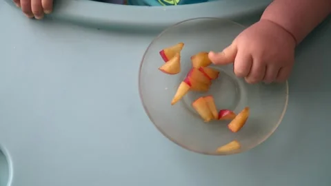 Hands of a small child take pieces of sliced peach from a plate Stock Footage 304363439
