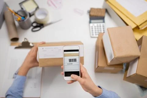 Hands with smartphone scans barcode on parcel box Foto stock