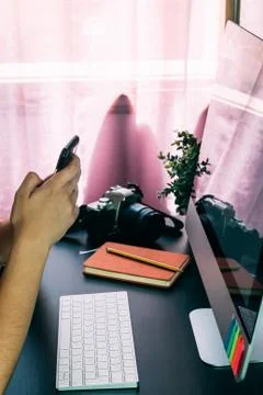 A Hands with smartphone working on computer at her home office Stock Photos