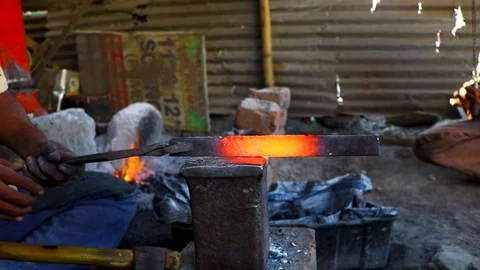 Hands of smith with hammer beat on glowing hot metal Stock Footage 107880095