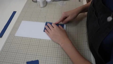 Hands smooth teal leather patch onto cardboard backing piece Stock Footage 339656533