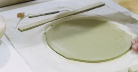 Hands Smoothing Circular Clay Piece on Flat Surface in Workshop Stock Footage 304412479