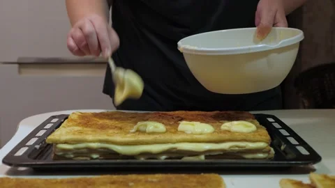 Hands smoothing cream across stacked pastry pieces 库存影片 342361757