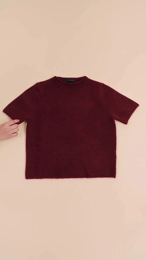 Hands smoothing maroon knitted t shirt on beige surface Stock-Footage 331774179