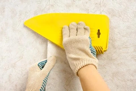 Hands smoothing wallpaper with scraper on the wall Stock Photos