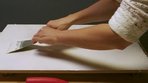 Hands smoothing white substance - putty, on wooden surface for art project Stock Footage 308668591