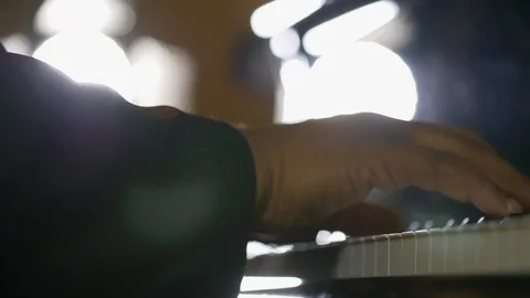 Hands in soft focus playing the piano with back lighting Video stock 108285873