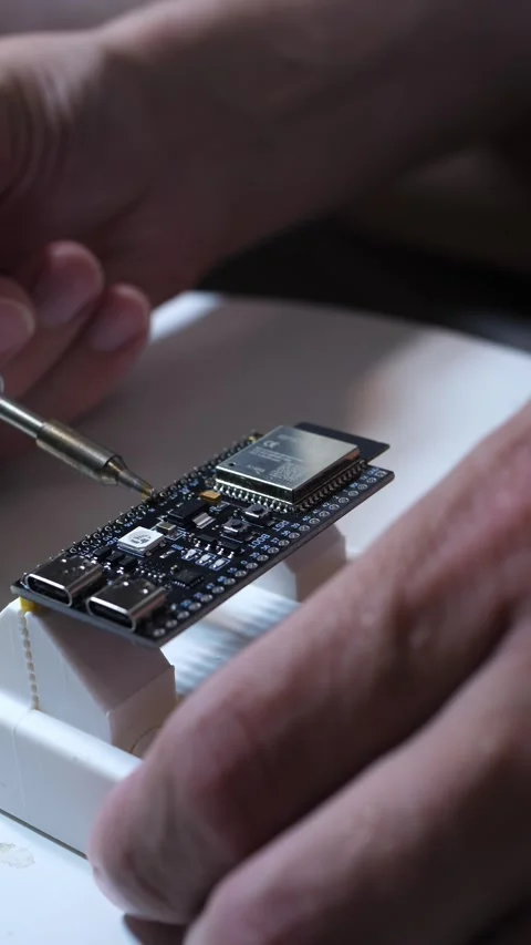 Hands soldering a microcontroller development board on a workbench Stock Footage 342520415
