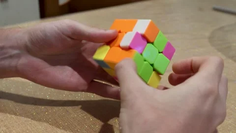 Hands Solving a Colorful 3x3 Puzzle Cube on a Table Stock Footage 344208168