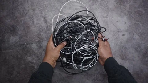 Hands sort through a tangled pile of black and white cables on a table Stock Footage 348121855