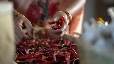Hands sorting dried red chillies in a woven basket for spice making Stock Footage 340958582
