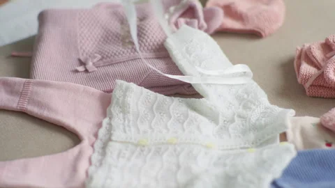 Hands sorting pink and white newborn clothing items Stock Footage 335509467